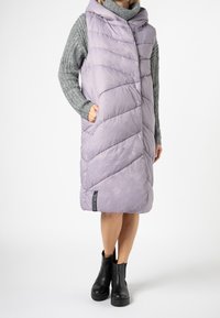 Ljuslila puffväst med bred huva, diagonalt quiltat mönster, två sidofickor och en svart logotyp på fållen.