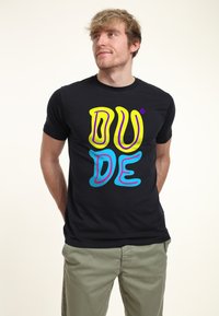 Camiseta negra de manga corta con un gráfico oversized en color amarillo y azul que dice "DUDE"; hecha de una tela transpirable, con un diseño ajustado.