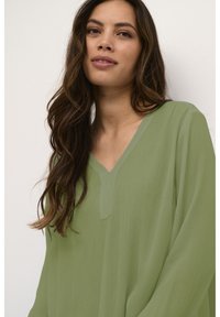 Lichtgroene, gestructureerde blouse met een V-hals en lange mouwen. Losse pasvorm met een subtiel verticaal streepjespatroon.