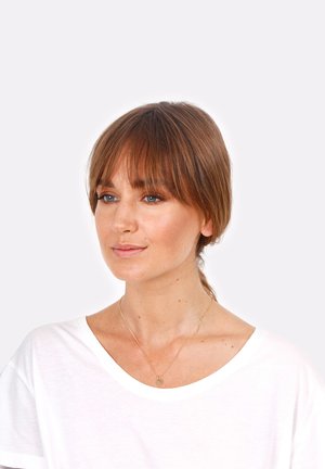 Weißes T-Shirt, goldene Halskette mit einem runden Anhänger, glatte Haut, schulterlanges Haar mit Pony, dezentes Make-up, heller Hintergrund.
