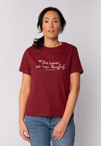 Bordeauxfarbener Baumwoll-T-Shirt mit kurzen Ärmeln und Rundhalsausschnitt, das weißen Text in einer verspielten Schriftart zeigt, der lautet: "Das Leben ist kein Ponyhof."