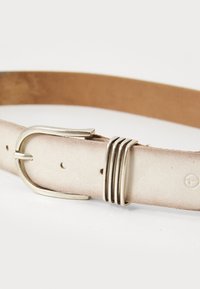 Ceinture en cuir de couleur claire avec une boucle en métal argenté et trois accents métalliques horizontaux. Texture lisse avec plusieurs trous d'ajustement.