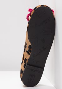 Semelle de chaussure imprimée léopard avec motifs en relief de chaussons de ballet et détails de pompons roses sur la partie supérieure de la chaussure.
