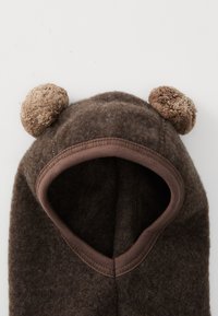 Barna, puha fleece balaclava, kerek pom-pom fülekkel és az arcnyílás barna bordás anyaggal díszítve.