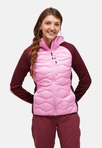 Giacca a vento trapuntata rosa con cappuccio e maniche in fleece bordeaux. Caratterizzata da tasche con zip e un collare alto. Texture liscia con motivo a onde.