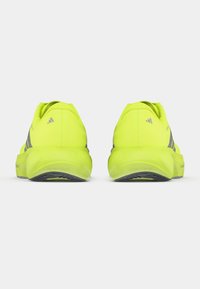 Leuchtend gelbe Laufschuhe mit strukturiertem Design, grauen Akzenten und einer gepolsterten Sohle. Die Fersenkappe sitzt eng anliegend. Leichtes Design.