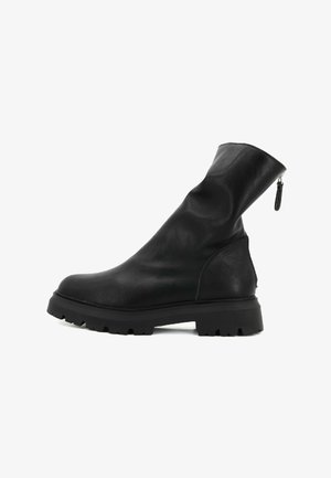 Stivale alla caviglia in pelle nera con un gambale morbido, superficie testurizzata, suola spessa e dettaglio con zip sul retro per una facile calzata.