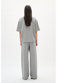 Grijze loungewear set met een ontspannen pasvorm, kort mouwtop en wijde broekspijpen, gemaakt van zachte, gestructureerde stof.