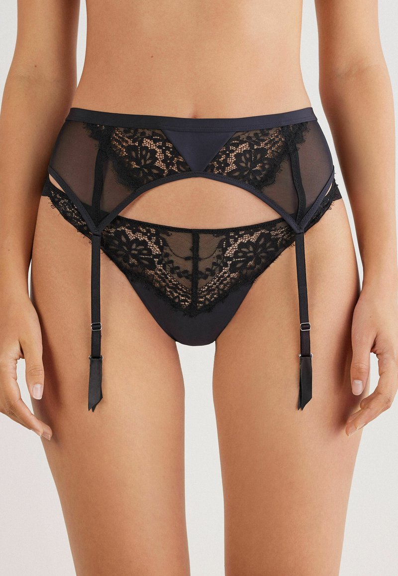 Sort lingeri med gennemsigtig mesh og blonder, med et cut-out design, justerbare stropper og dekorative detaljer.