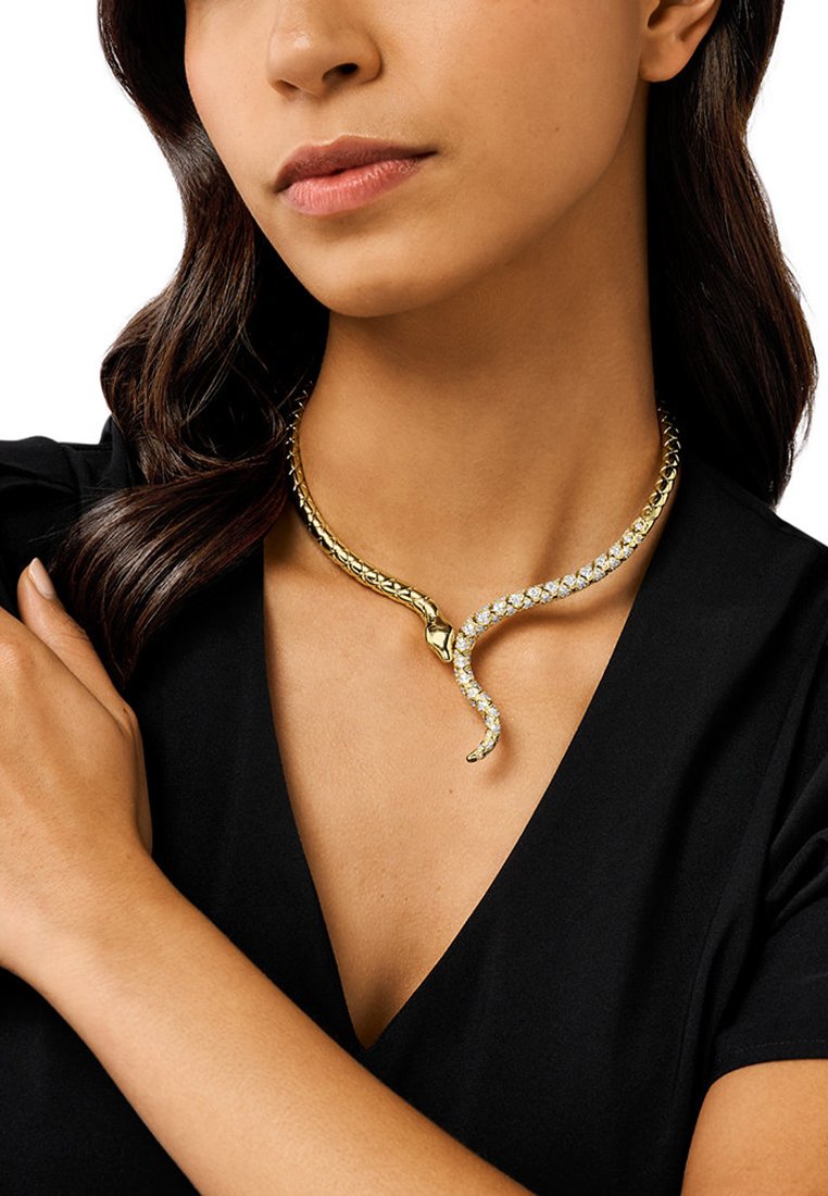 Collana choker in tono oro con design a serpente, caratterizzata da cristalli trasparenti e scintillanti lungo il corpo e una catena a maglie texture.