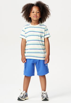 T-shirt à manches courtes rayé avec une poche poitrine, shorts cargo bleus et baskets. Le t-shirt présente des rayures horizontales vertes et bleues.