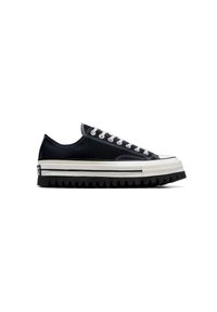 Zapatilla de lona negra con suela de goma blanca, que presenta una gruesa banda negra, acentos blancos y un diseño clásico de cordones.