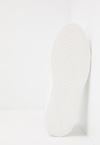 White sneaker sole with a textured, grid pattern. Material appears rubber with smooth edges and a flat profile. No branding visible.