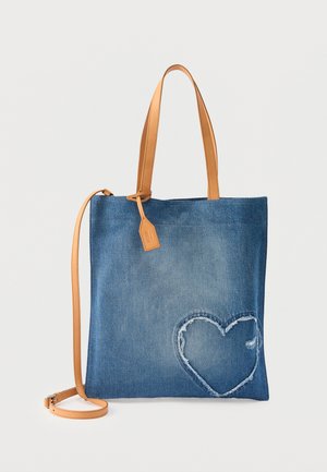 Plava traper torba s ručkama od smedene kože išivenim dizajnom srca u donjem desnom kutu.