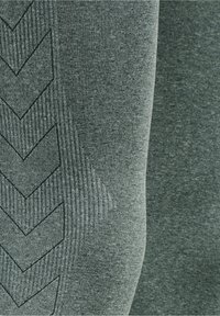 Close-up of textured gray fabric with ribbed patterns and black outlined chevron designs on one side.