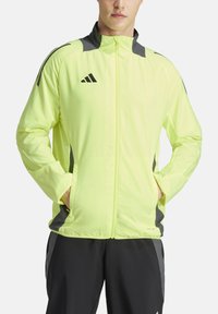 Veste de sport jaune fluo avec des accents gris, en tissu léger, à fermeture éclair intégrale et poches latérales. Elle dispose d'un col montant et d'un détail logo.
