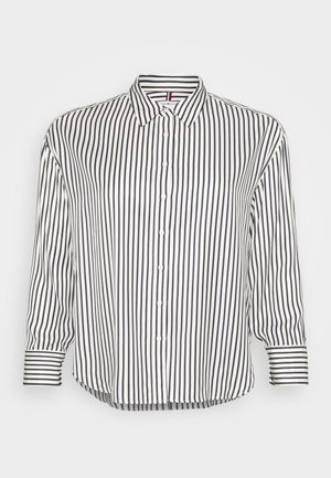 Chemise à col avec des rayures horizontales et verticales bleu marine et blanches, dotée d'une fermeture à boutons et d'un ourlet légèrement courbé.