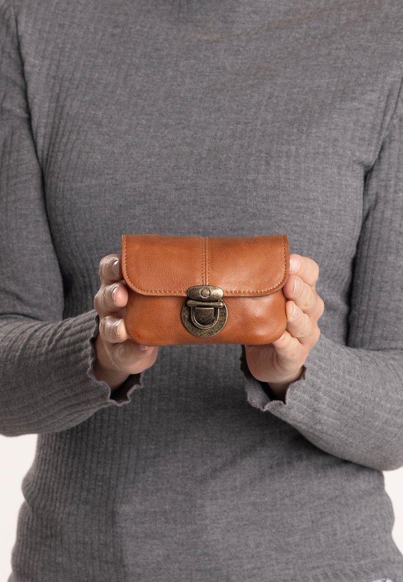 Smeđa kožna torbica zaokruženog oblika, s preklopom i brončanim kopčom. Glatka tekstura s vidljivim detaljima šivanja.