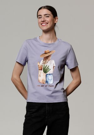 Lavendel Baumwoll-T-Shirt mit einer Grafik einer Figur mit einem Strohhut, die eine Aloe-Pflanze und eine Tragetasche hält, Text: "ICH BIN EINS VON DENEN."