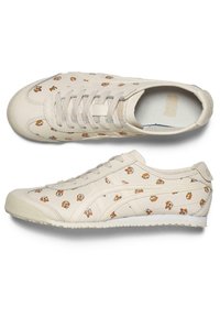 Baskets beige en cuir avec un motif de dessin animé répété. Le design comprend des lacets et une semelle texturée pour une meilleure adhérence.