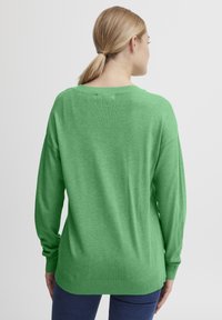 Pulover verde tricotat, cu guler rotund, mâneci lungi și manșete cu dantelă. Textură fină și croi relaxat, având un design cu umăr căzut.