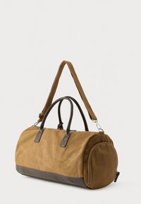Καφέ τσάντα duffel από καμβά με δερμάτινη βάση, δερμάτινες λεπτομέρειες, διπλές λαβές και ρυθμιζόμενο ιμάντα ώμου για ευελιξία.