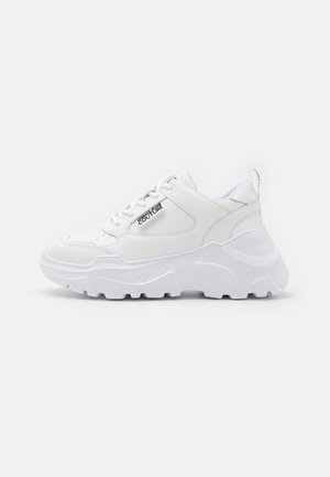 Sneakers blancs chunky avec une tige en cuir lisse, une semelle texturée contrastante et un design à lacets. Présente un détail de logo sur le côté.