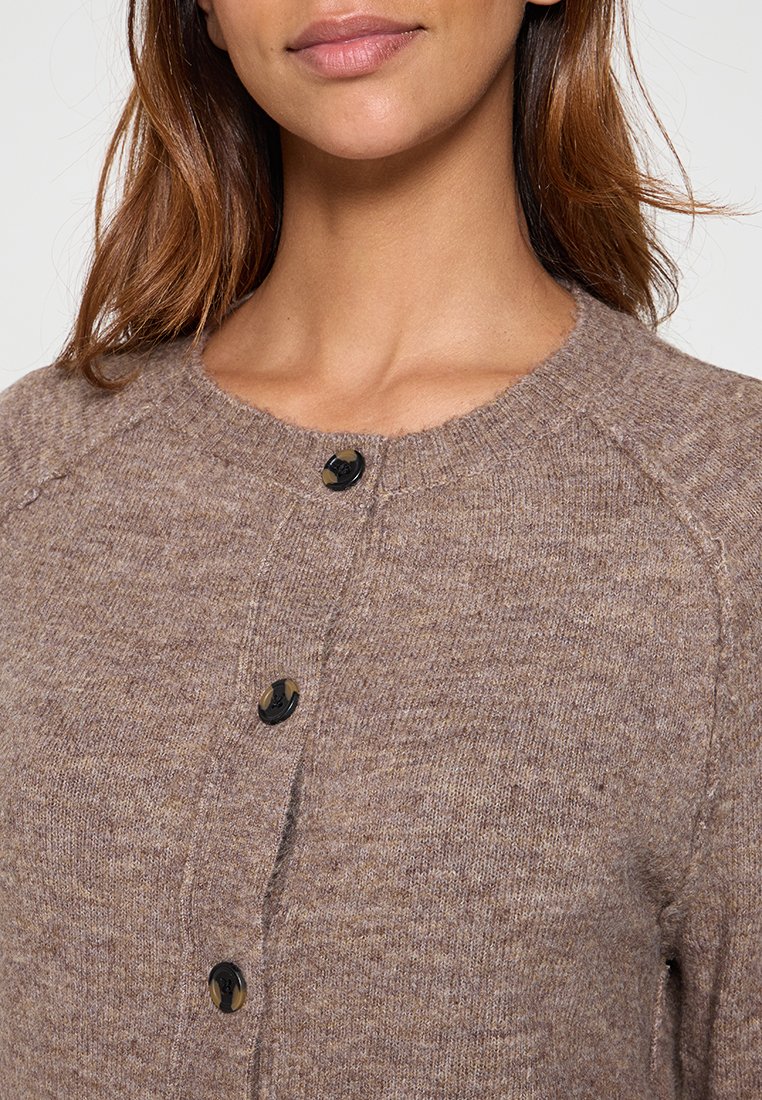 Cardigan en tricot marron avec un col rond, doté de boutons noirs sur le devant et d'un tissu doux et texturé.