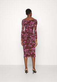 Vestido floral marrón con mangas largas y diseño sin hombros. Presenta patrones florales en rosa y verde, con detalles fruncidos en la parte posterior.