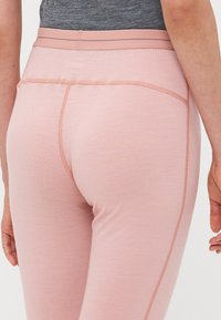 Lys rosa leggings med en jevn tekstur, med bred midjebånd og subtile sømdetaljer langs sidene.