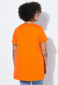 Orange kortærmet T-shirt lavet af blødt stof, med rund halsudskæring, afslappet pasform og en længere bagkant.