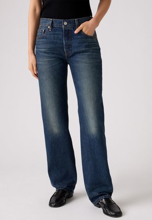 Bredde jeans i mørkeblå denim, med høy midje, subtil fading og frontlommer. Kombinert med svarte sko.