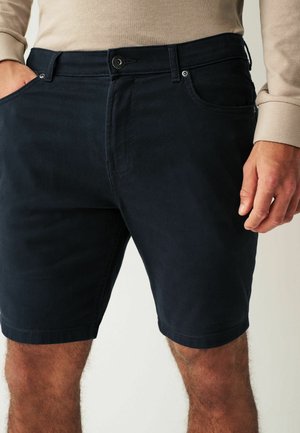 Mørkeblå bomulds shorts med frontlommer, knaplukning og en let tekstureret overflade. Helt slutter over knæet.