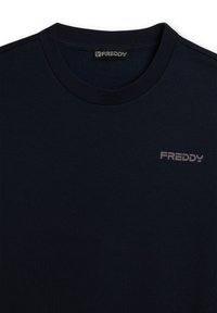 Camiseta de algodón azul marino con cuello redondo, que presenta una textura suave y un pequeño logo gris "FREDDY" en el pecho. Diseño simple y sólido.