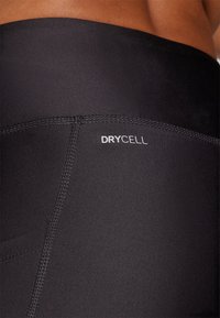 Crne atletske tajice od rastezljivog materijala s istaknutim "DRYCELL" logotipom na pojasu, s ravnim šavovima za udobnost.
