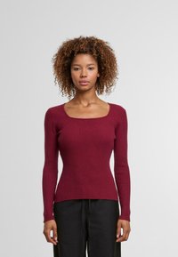 Burgundské žebrované pletené svetr s čtvercovým výstřihem, dlouhými rukávy a přiléhavým střihem. Měkká textura a hladký povrch.