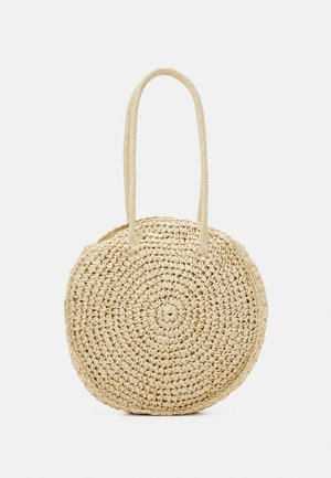 Borsa rotonda in paglia intrecciata beige con doppi manici lunghi, progettata per essere portata a spalla, mostrata su sfondo bianco.