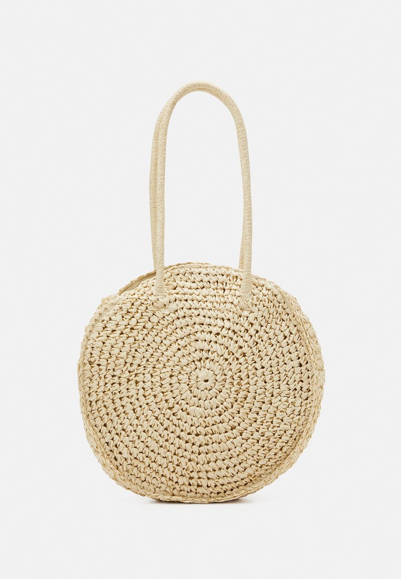 Sac à main rond en paille tressée beige avec doubles poignées longues, conçu pour être porté à l'épaule, présenté sur fond blanc.