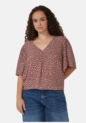 Blouse couleur rouille avec motif à pois blancs, décolleté en V et manches courtes flottantes. Fabriquée en tissu léger avec une coupe décontractée.