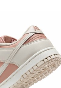 Chaussure avec une tige en cuir beige et rose, dotée d'un talon texturé, d'une semelle en caoutchouc blanche et de coutures visibles. Pas de lacets visibles.
