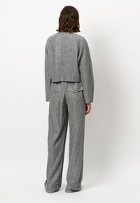 Grijze textuur cropped jack met een rechte pasvorm, gecombineerd met losse grijze broeken met achterzakken en een subtiel patroon.
