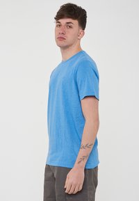 T-shirt azzurro chiaro a maniche corte con colletto rotondo, caratterizzato da un logo discreto sul lato sinistro del petto, realizzato in un morbido tessuto testurizzato.