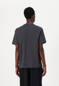 Mørkegrå kortærmet t-shirt med rund hals og lige snit, lavet af glat bomuldsstof uden tydelige mønstre eller dekorative elementer.
