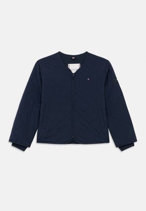 Laineetettu tummansininen takki, jossa on pyöreä kaula-aukko, etuvetoketju ja huomaamaton logo yksityiskohtana rinnassa. Varusteena elastiset hihansuut ja sivutaskut.