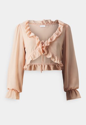 Blusa corta de color durazno en una tela ligera con collar y puños con volantes, que presenta un cierre con lazo y un dobladillo de volantes en capas.