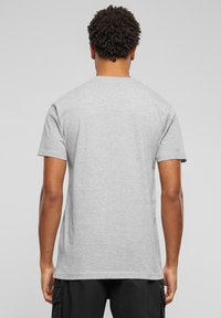Pilkas trumpas rankovė t-shirt, pagamintas iš medvilnės mišinio, klasikinio apvalaus kaklo ir laisvo silueto, su lygiu tekstūru ir minimalizmo dizainu.