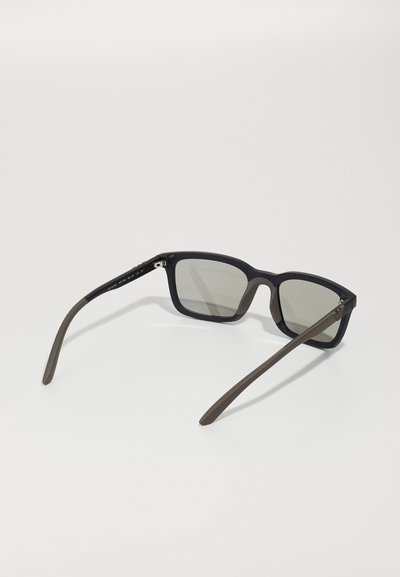 Ochelari de soare rectangulării negri cu lentile gri și finisaj mat. Bratele sunt de culoare verde închis cu un detaliu subtil de branding.