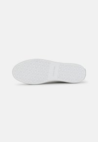 Semelle de sneaker blanche présentant un motif texturé avec le logo Calvin Klein et des accents circulaires. Finition lisse, matériau en caoutchouc.