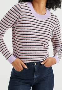 Randig tröja med lila rund hals, svarta, rosa och vita horisontella ränder, samt ribbade ärmslut, ihop med mörka jeans.