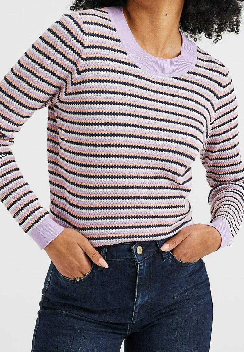 Randig tröja med lila rund hals, svarta, rosa och vita horisontella ränder, samt ribbade ärmslut, ihop med mörka jeans.